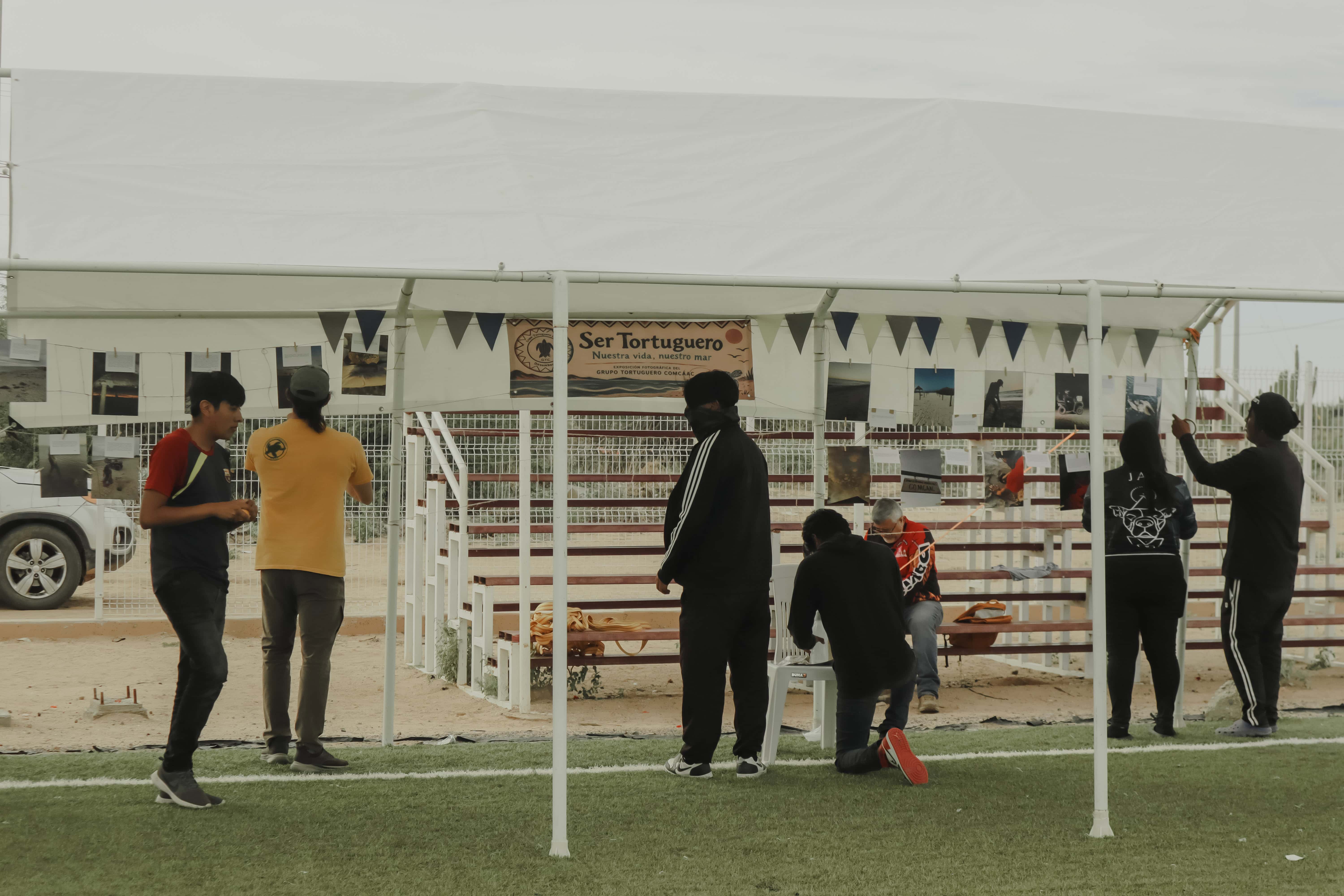 Preparativos de la exposición fotográfica bajo la carpa, en la cancha.